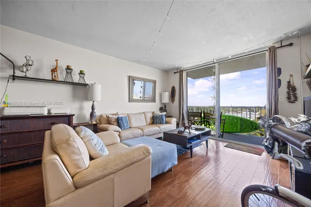 a living room with furniture large window and wooden floor