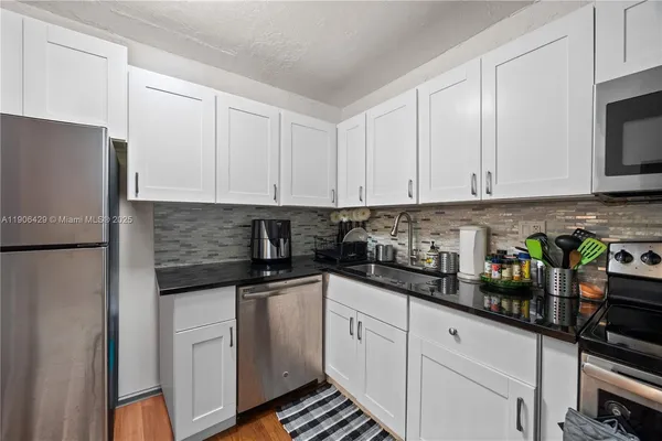 a kitchen with stainless steel appliances granite countertop white cabinets sink and a refrigerator