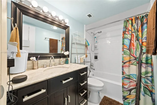 a bathroom with a granite countertop sink a toilet a mirror a vanity and shower