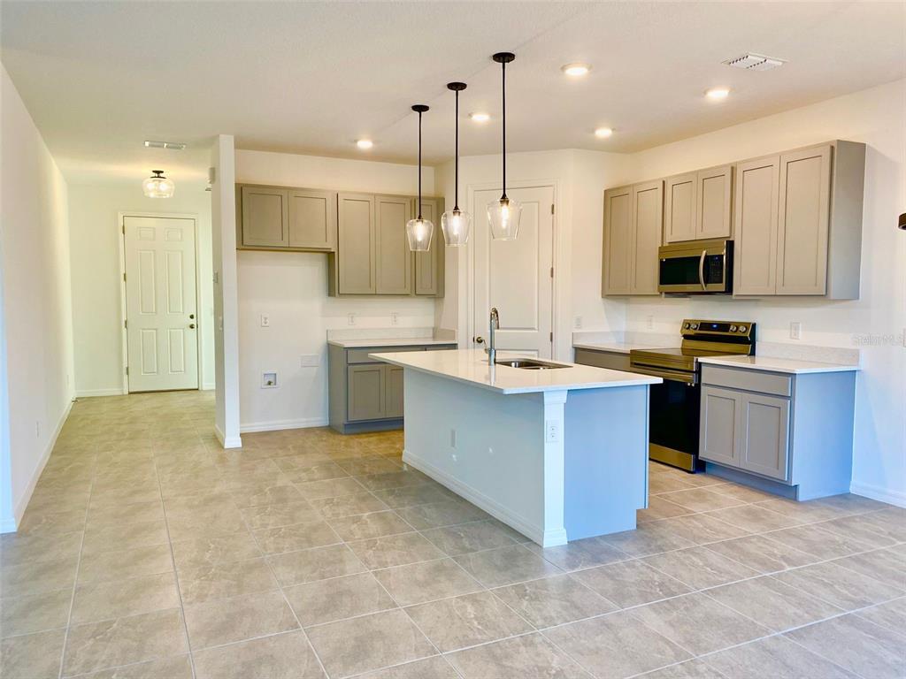 2190 Derwent Drive Davenport, FL 33896 - Photo 25 of 30 a large kitchen with stainless steel appliances kitchen island granite countertop a stove a sink a counter top space and cabinets