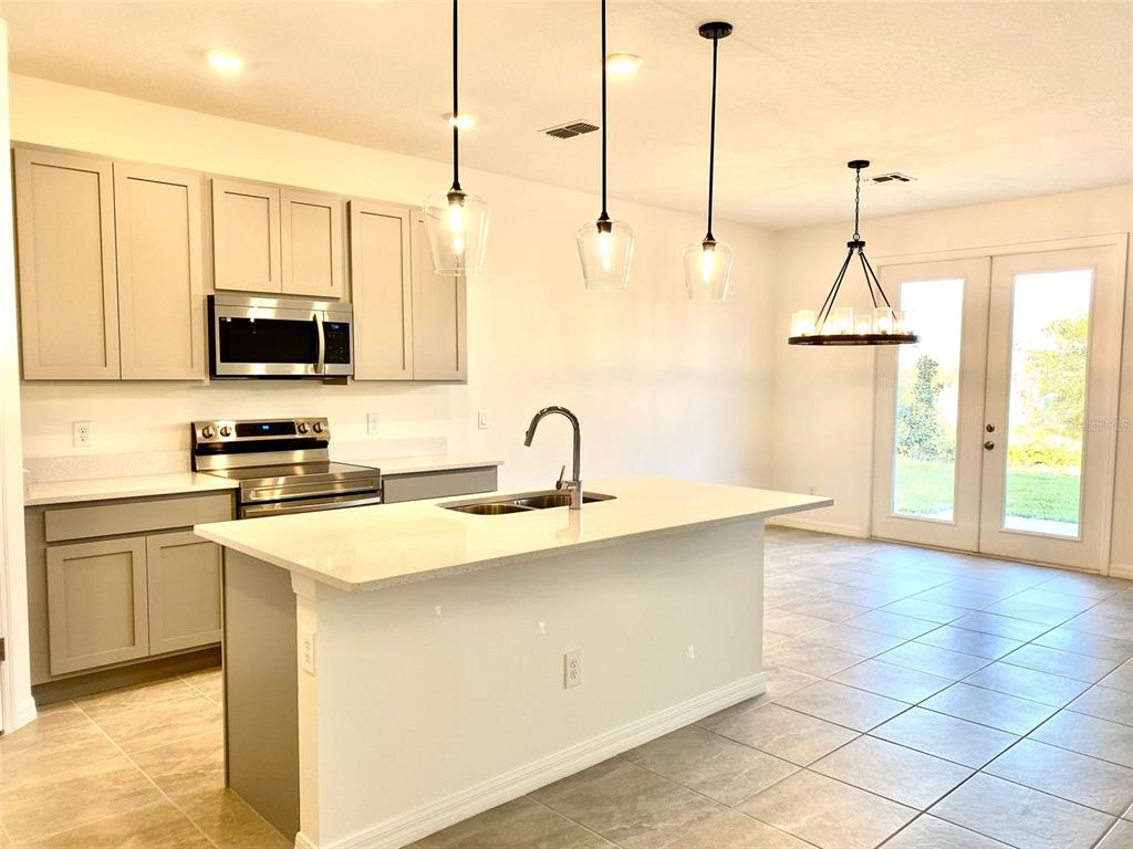 2190 Derwent Drive Davenport, FL 33896 - Photo 4 of 30 a kitchen with stainless steel appliances granite countertop a sink a stove and a wooden floors