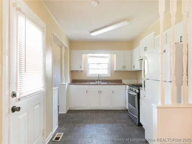 a kitchen with granite countertop white cabinets and white appliances