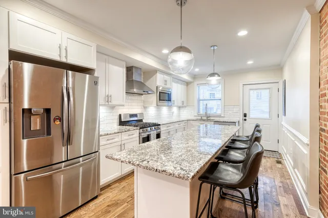 a kitchen with refrigerator a sink and chairs