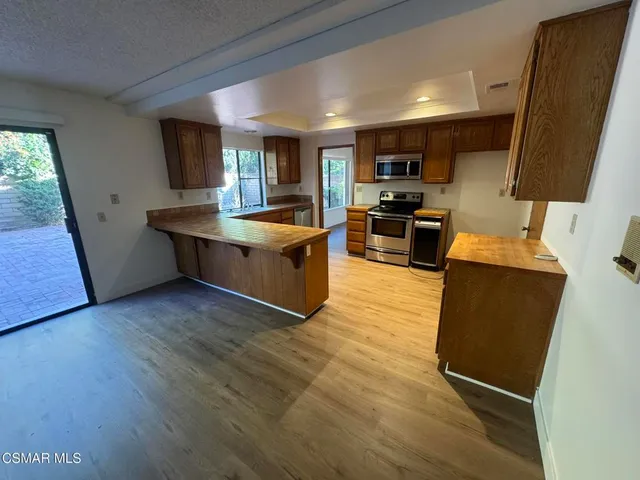 a large living room with stainless steel appliances granite countertop a couch and a wooden floors