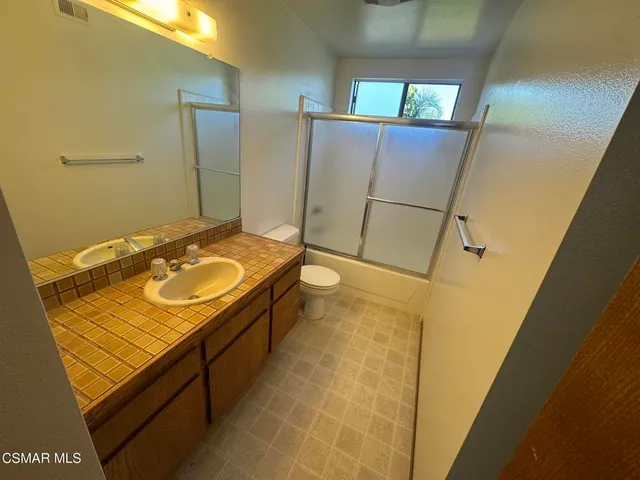 a view of an empty room with windows & cabinet