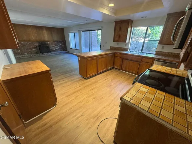 a kitchen with stainless steel appliances wooden cabinets a stove top oven a sink and a window