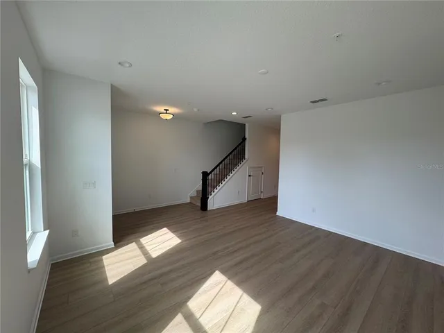 a view of empty room with wooden floor and fan