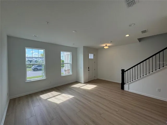 an empty room with wooden floor and windows