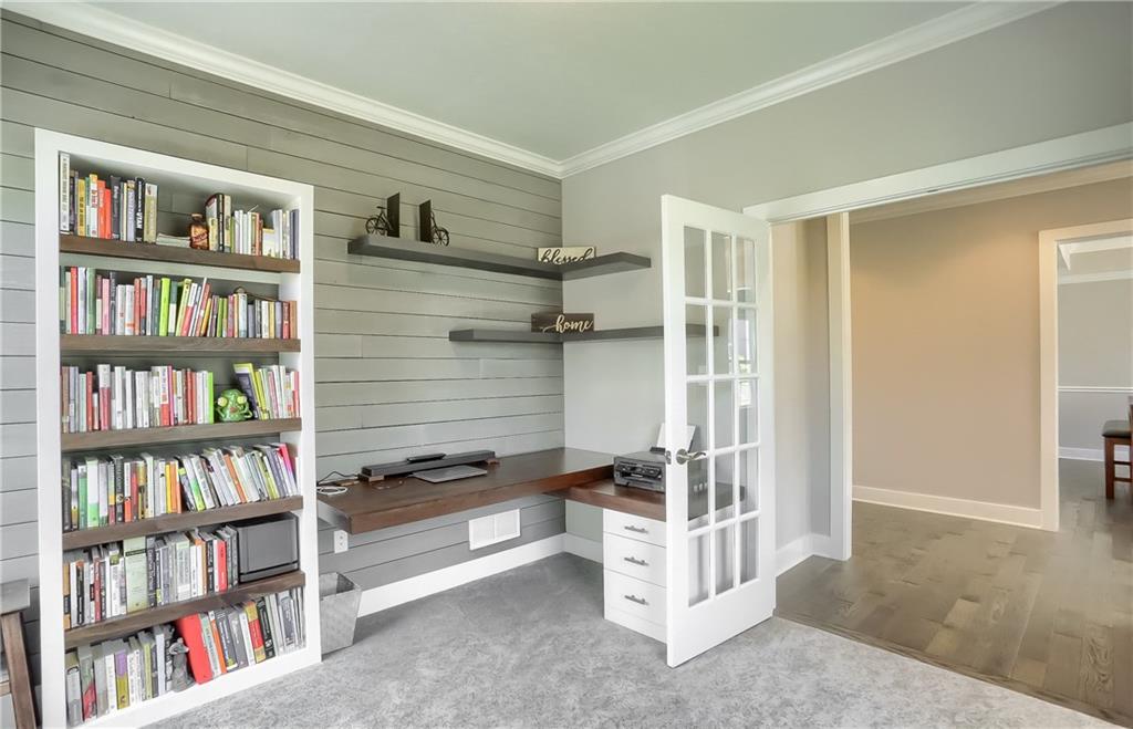 A home office has French doors for privacy and a custom shiplap accent wall.
