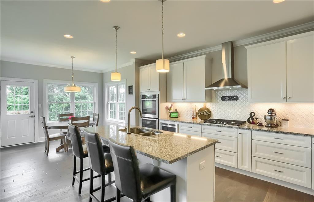 The open layout kitchen features stainless steel appliances including a gas stovetop and double ovens. 