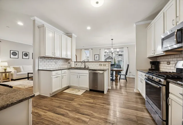 a kitchen with granite countertop a stove a sink dishwasher and a refrigerator with wooden floor