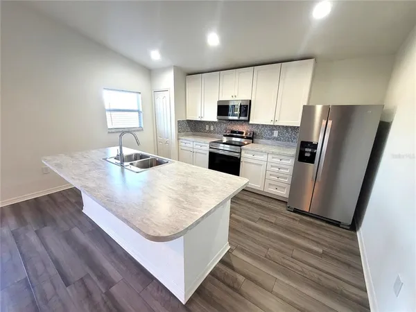 a kitchen with stainless steel appliances a kitchen island hardwood floor sink and stove