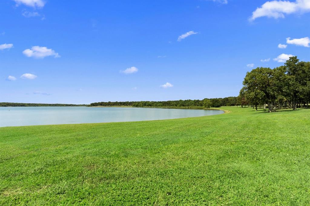 3344 Duncan Way Corinth, TX 76210 - Photo 35 of 38 Expansive green lawn bordering a tranquil body of water, complemented by mature trees lining the distant shore