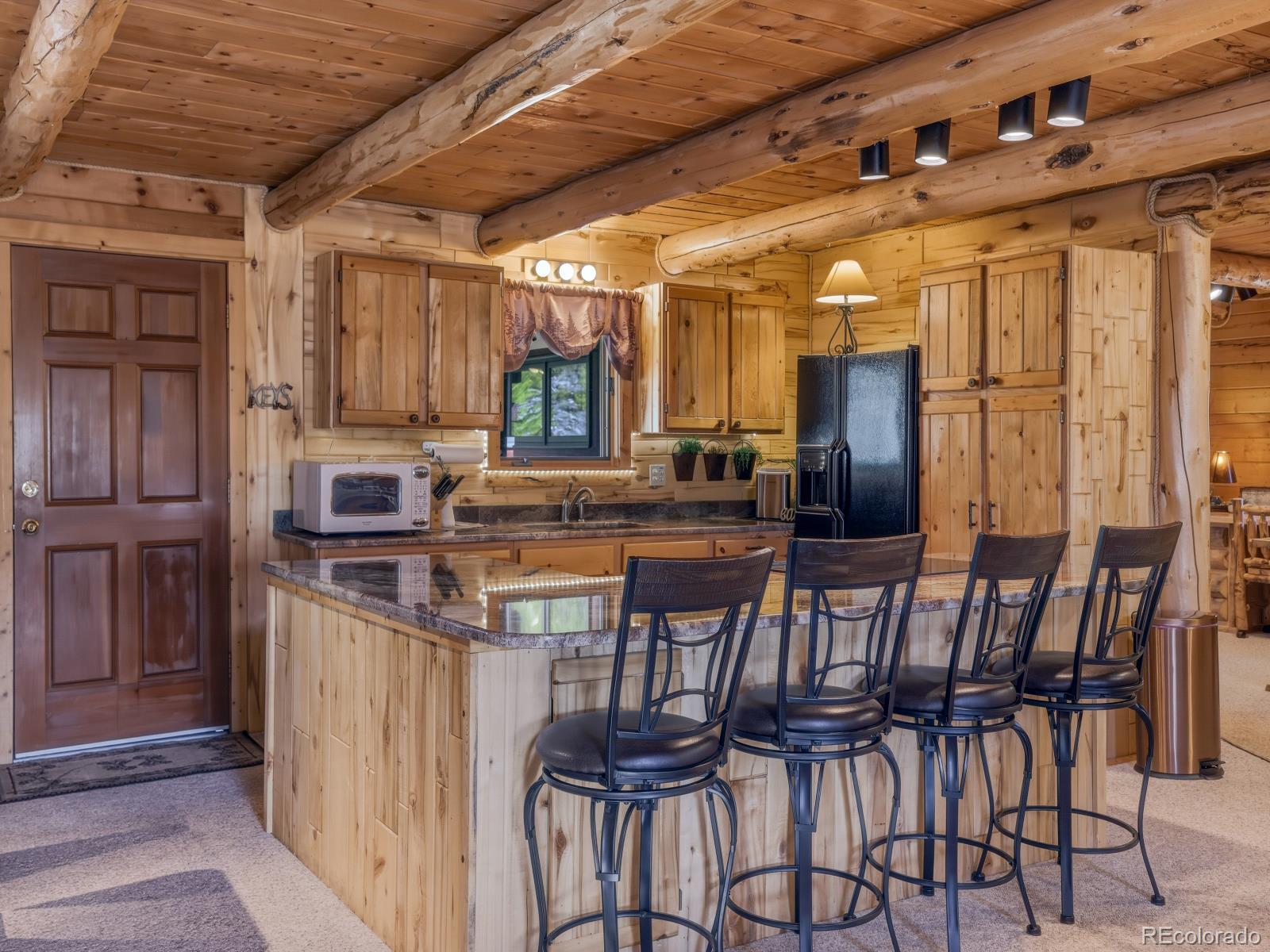 341 Anderson Road Walden, CO 80480 - Photo 27 of 50 a kitchen with stainless steel appliances kitchen island granite countertop a table chairs and a refrigerator