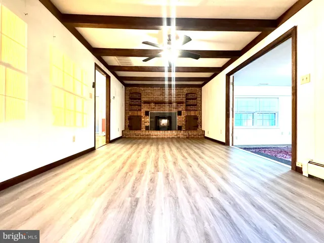 a view of an empty room with wooden floor fireplace and a window