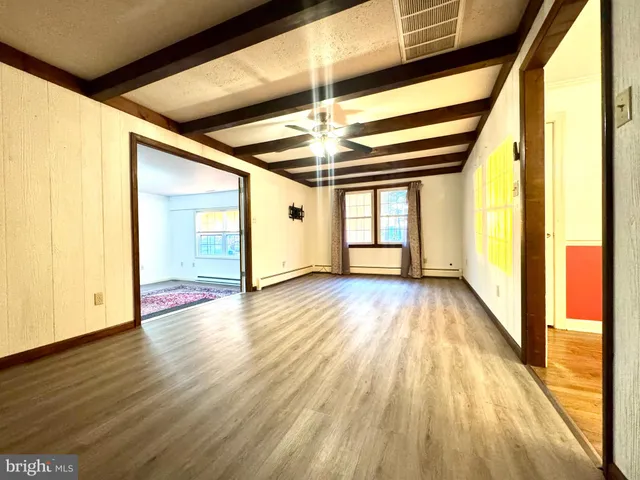 a view of empty room with wooden floor and fan