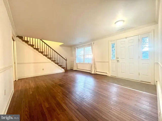 a view of an empty room with wooden floor and stairs