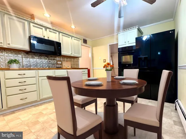 a kitchen with stainless steel appliances kitchen island granite countertop a table chairs and a refrigerator
