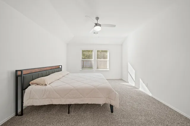 a large bed sitting in a bedroom next to a window and a chandelier