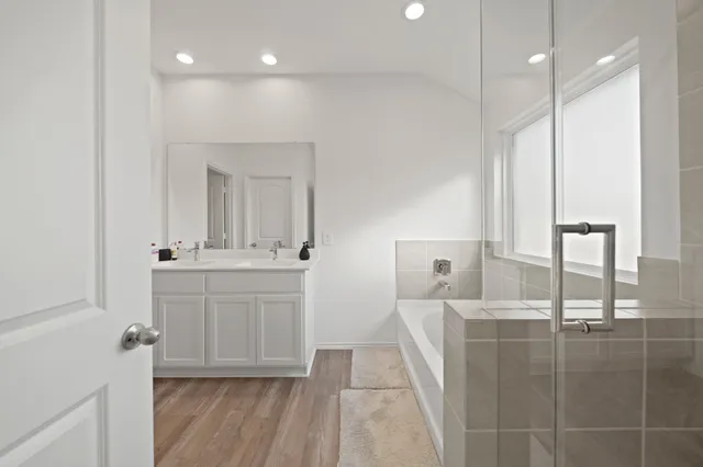 a bathroom with a double vanity sink a mirror and a bathtub