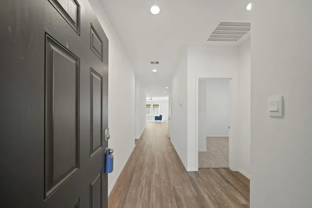 a view of a hallway with wooden floor and a bathroom
