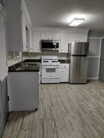 a kitchen with a sink wooden floor and stainless steel appliances