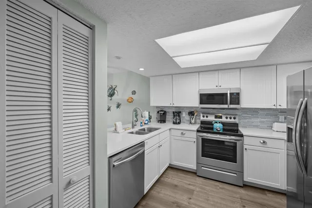 a kitchen with stainless steel appliances a white stove top oven and white cabinets