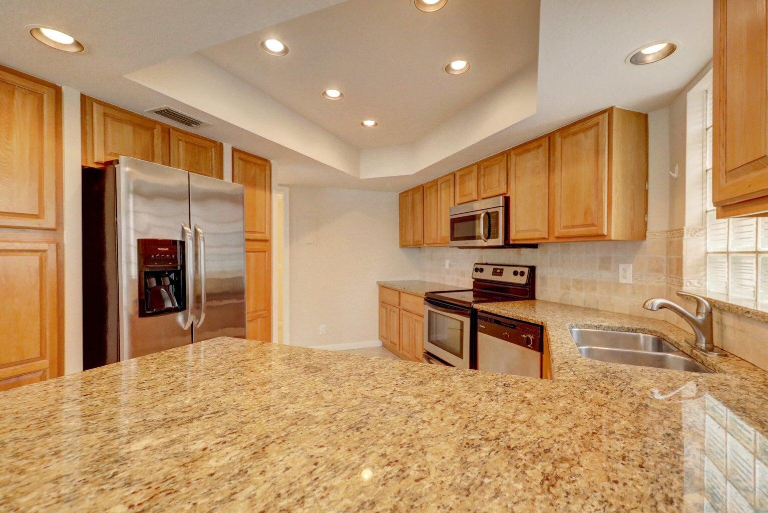 4356 Hazel Avenue, Unit C Palm Beach Gardens, FL 33410 - Photo 11 of 16 a kitchen with stainless steel appliances granite countertop a refrigerator stove top oven and sink