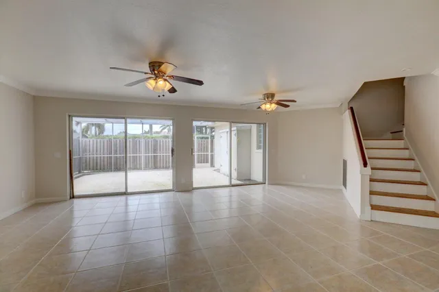 a view of an empty room with a ceiling fan and window