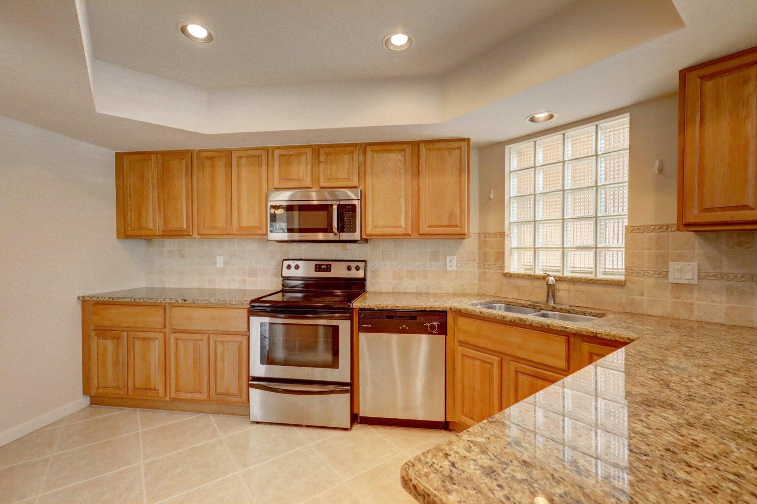 4356 Hazel Avenue, Unit C Palm Beach Gardens, FL 33410 - Photo 10 of 16 a kitchen with stainless steel appliances granite countertop a sink a stove a microwave a sink a refrigerator and cabinets