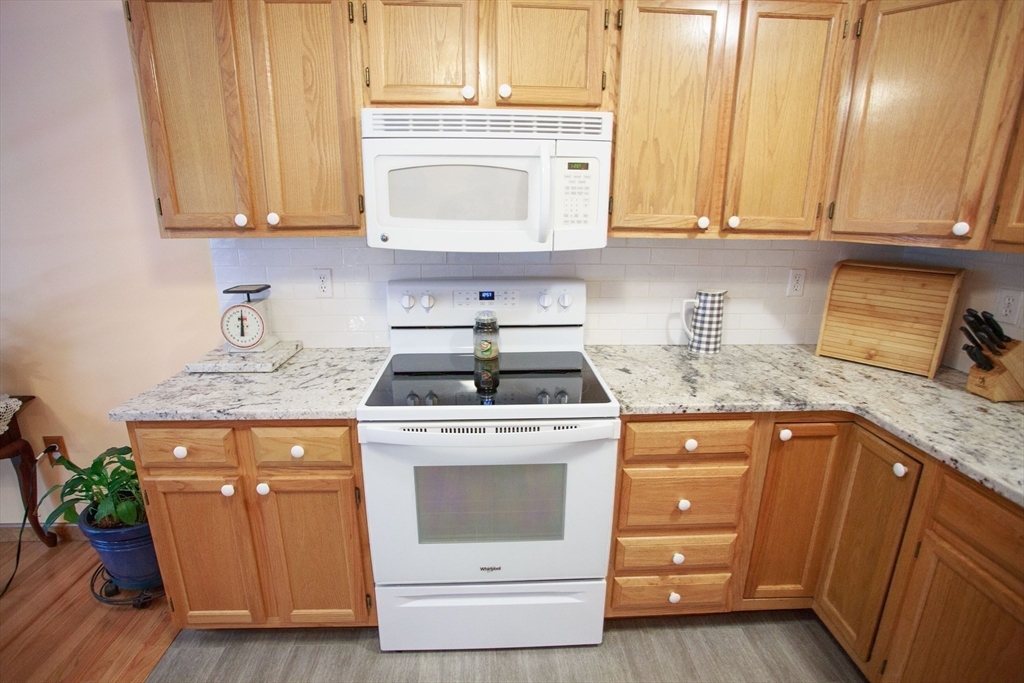 665 Center Street, Unit 311 Ludlow, MA 01056 - Photo 6 of 24 a kitchen with granite countertop stainless steel appliances white cabinets granite counter tops and a wooden floor
