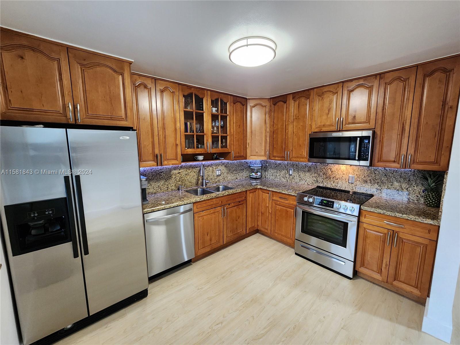 296 Racquet Club Road, Unit 203 Weston, FL 33326 - Photo 8 of 43 a kitchen with granite countertop wood cabinets stainless steel appliances and a window