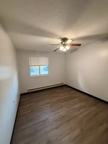 an empty room with wooden floor chandelier fan and windows