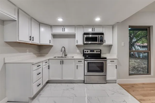 a kitchen with white cabinets and stainless steel appliances