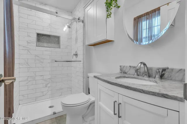 a bathroom with a granite countertop sink a toilet and a mirror
