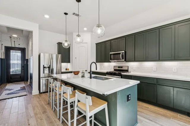 a kitchen with stainless steel appliances granite countertop a sink a stove and a wooden floors