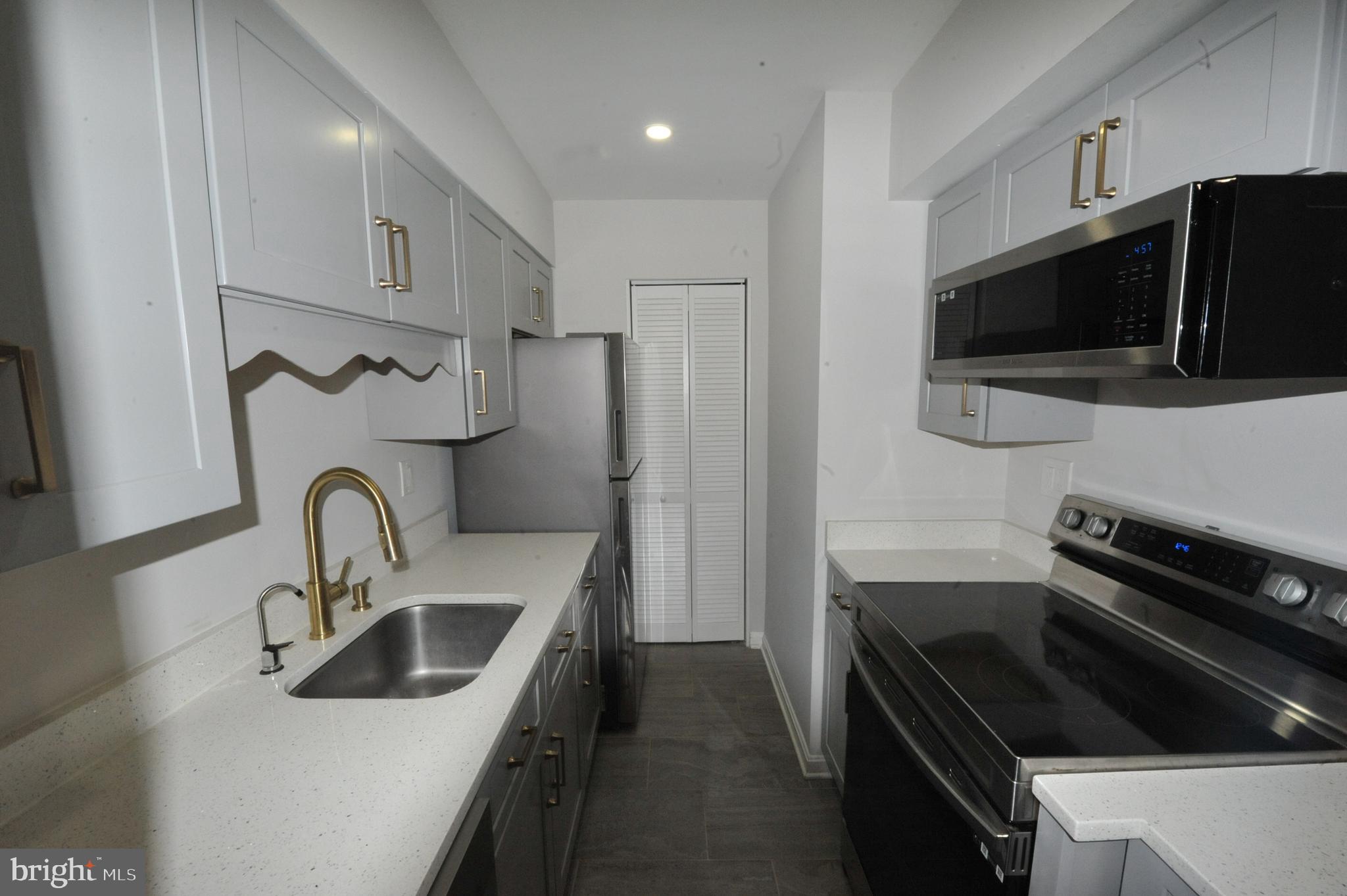 5900 K Surrey Hill Place, Unit 697 Springfield, VA 22152 - Photo 14 of 32 a kitchen with stainless steel appliances a sink a stove a microwave and cabinets