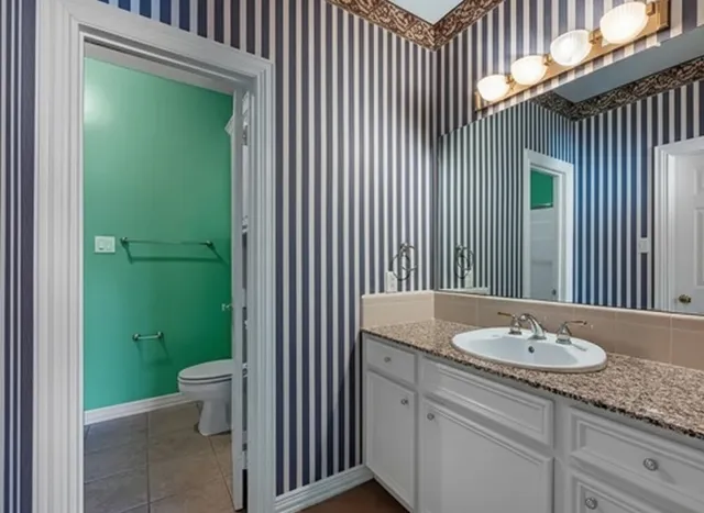 a bathroom with a granite countertop sink a toilet and a mirror