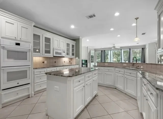 a kitchen with granite countertop white cabinets and white appliances