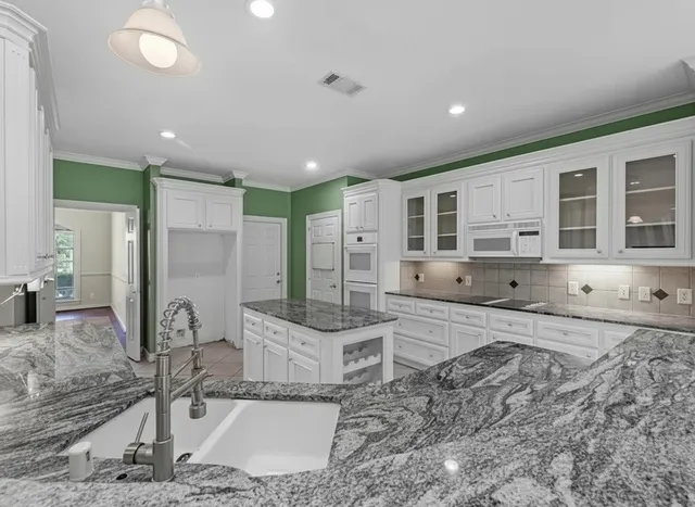 a large kitchen with stainless steel appliances granite countertop a granite counter top and a refrigerator