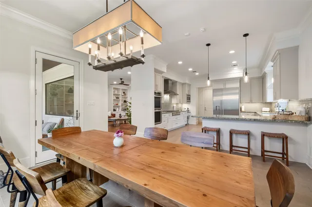 a kitchen with stainless steel appliances granite countertop a stove a dining table chairs and chandelier