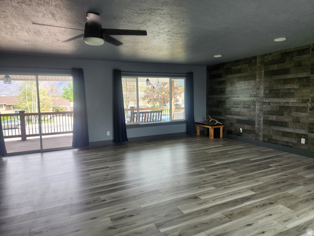 705 North 700 East Payson, UT 84651 - Photo 10 of 30 Spare room featuring a ceiling fan, a textured ceiling, wood walls, wood finished floors, and an accent wall