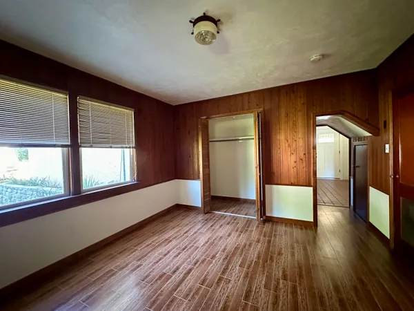 a view of empty room with wooden floor and fan