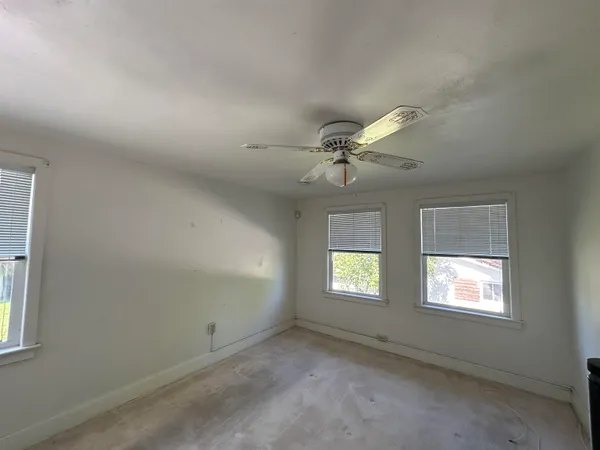 an empty room with windows and fan