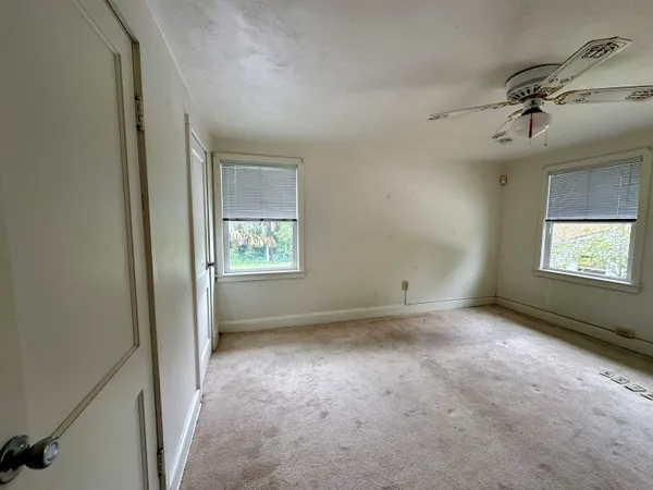 an empty room with windows and fan