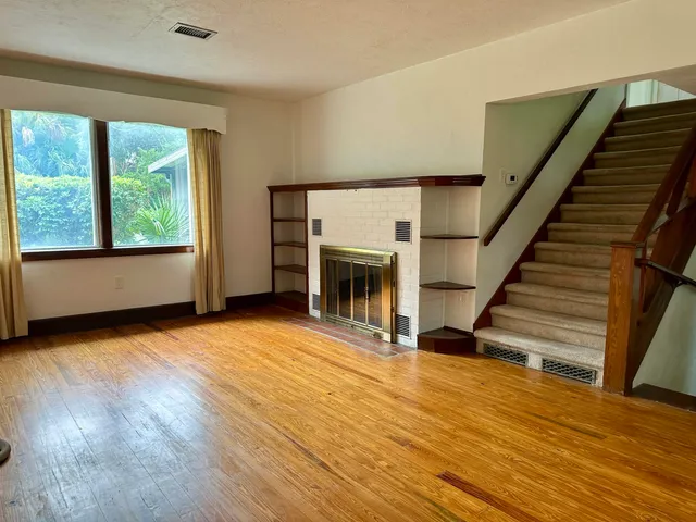 a view of empty room with wooden floor and fan