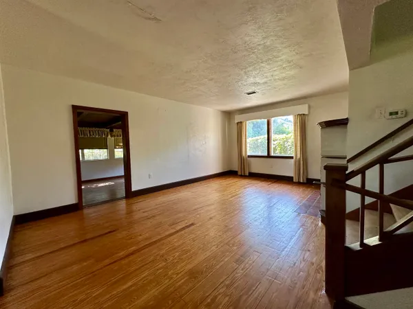 a view of an empty room with window and wooden floor
