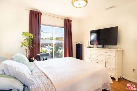 a bedroom with a bed and a flat tv screen on dresser