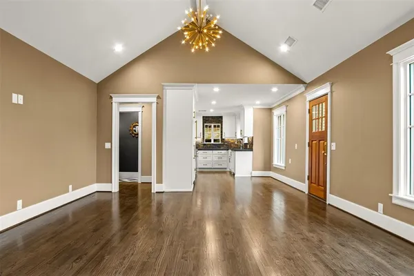 a view of a hallway with wooden floor and a kitchen