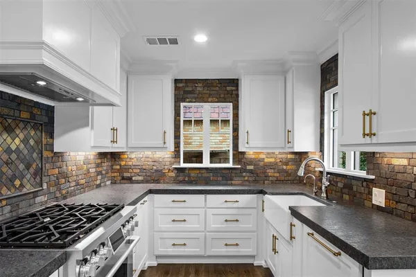 a kitchen with granite countertop a sink stove and cabinets